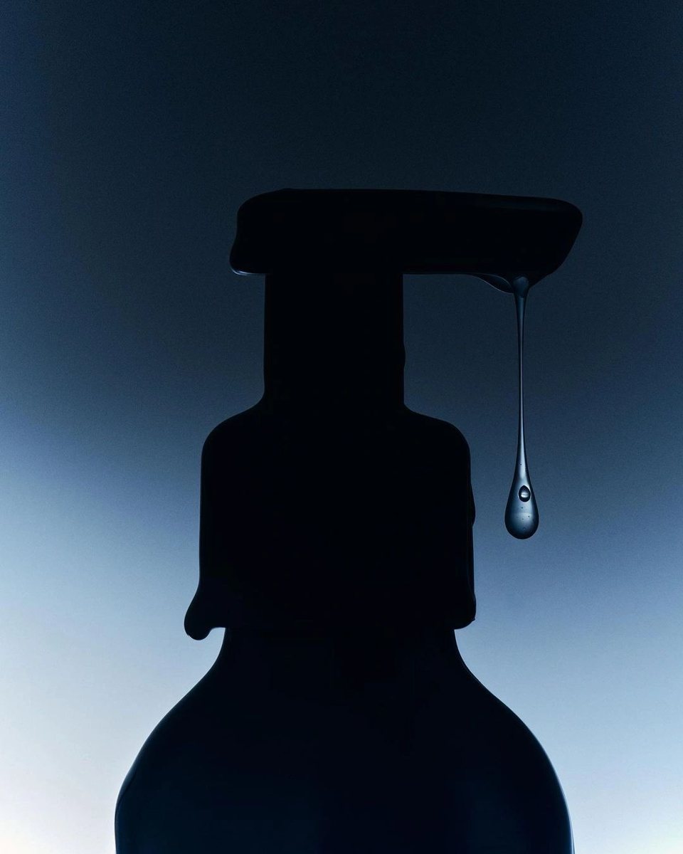 A dark bottle with a single drip